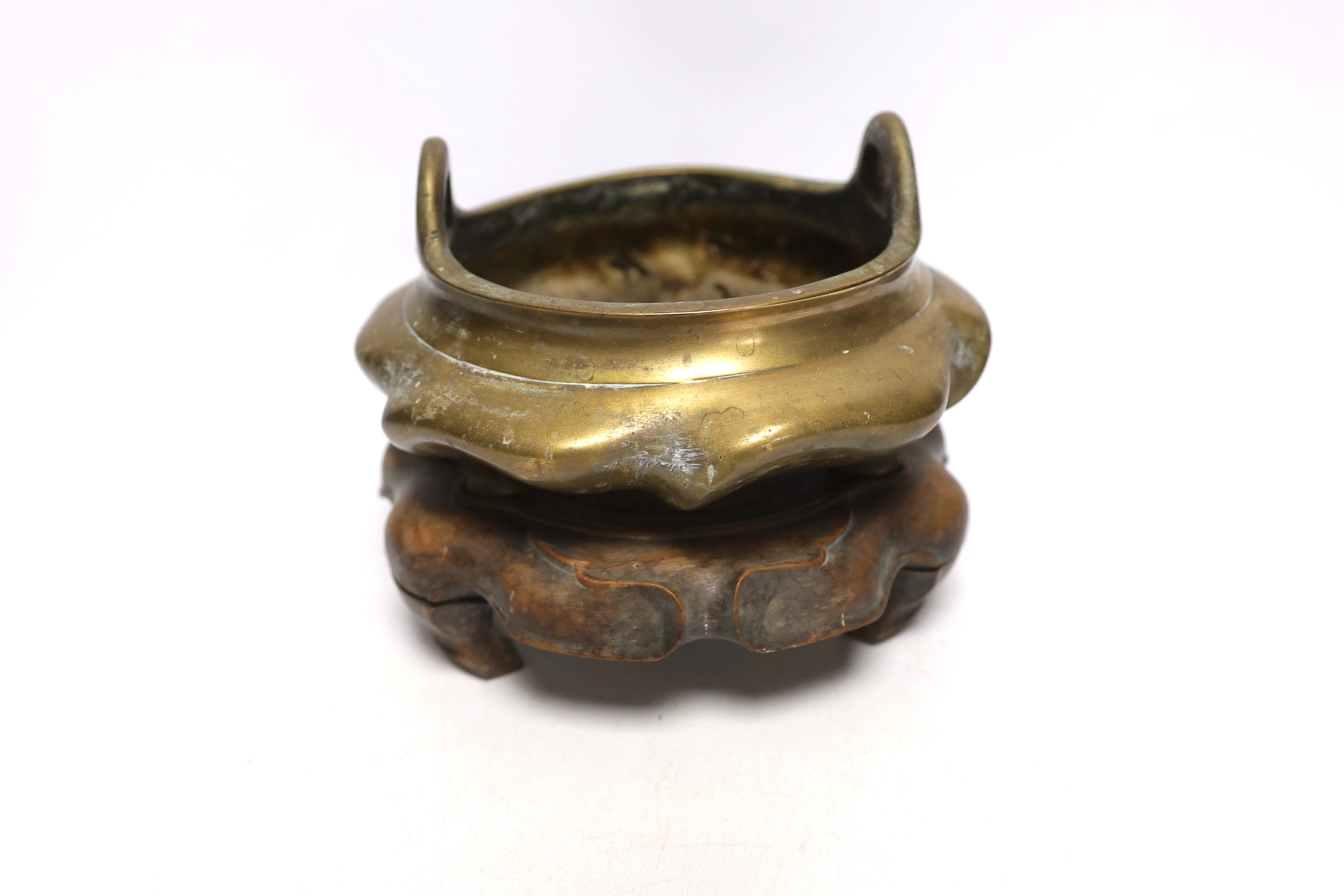 A Chinese bronze tripod censer with twin handles on hardwood stand, censer 19cm wide